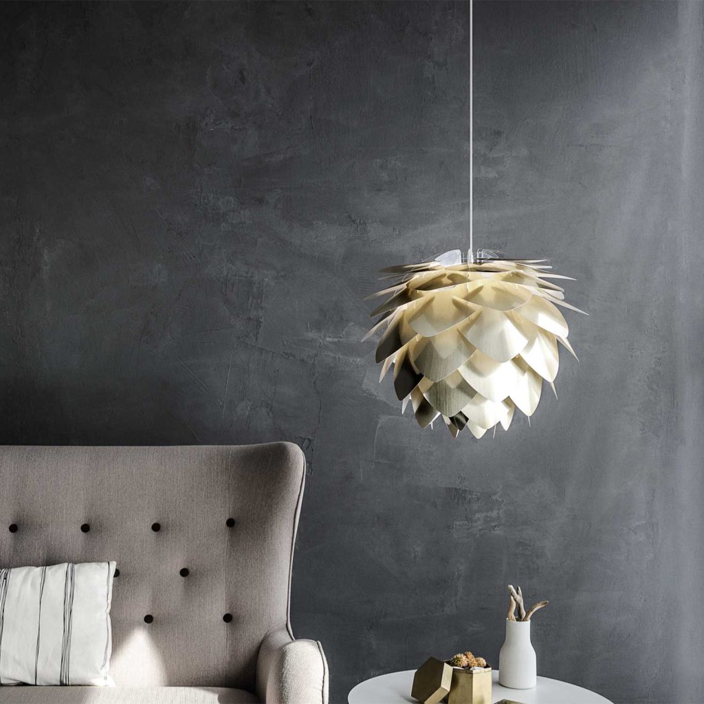 Skandinavischer Wohnstil Farben perfekt kombiniert: Grauer Sessel mit weiß-gestreiftem Kissen, weiße Pendelleuchte mit Blätterstruktur und weiße Vase auf hellem Beistelltisch.