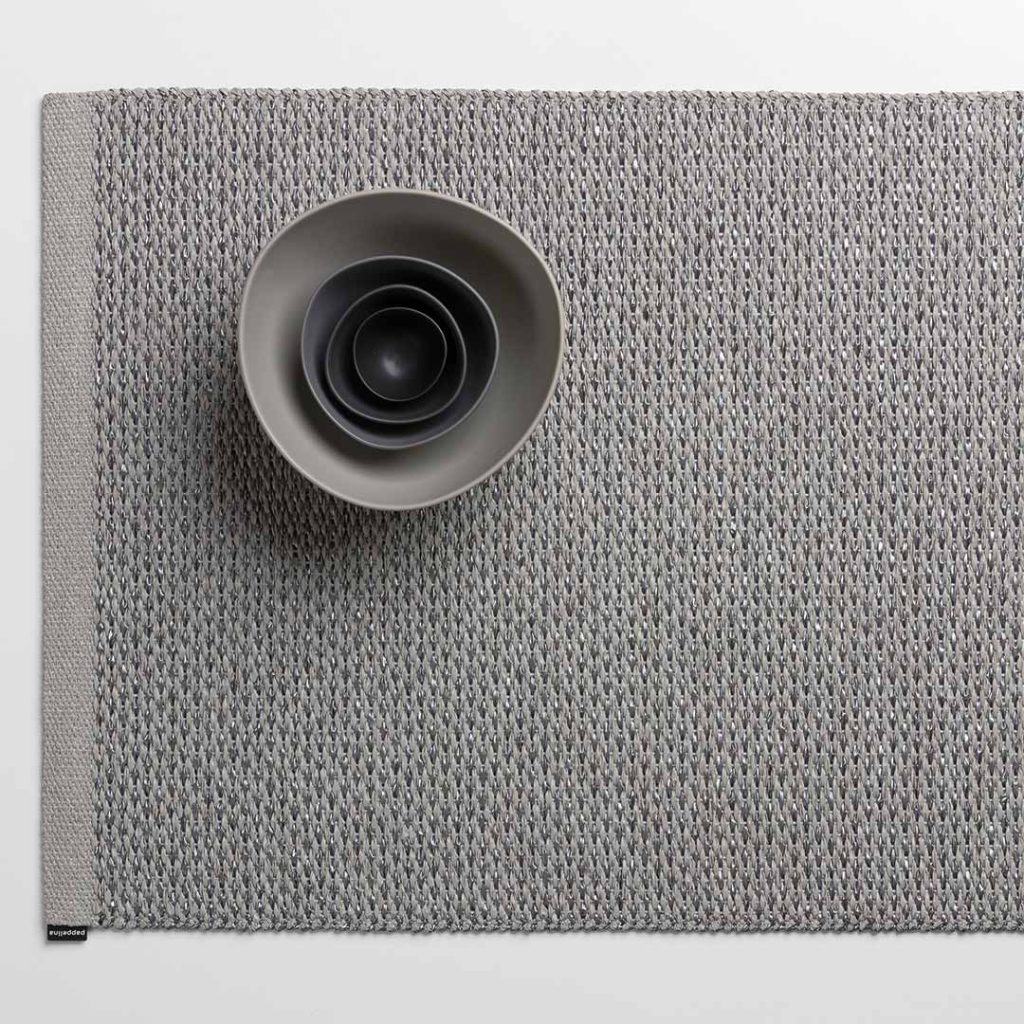 Der graue Pappelina Teppich ist aus aus pflegeleichtem Kunststoff und handgewebt. Ganz schön hygge!